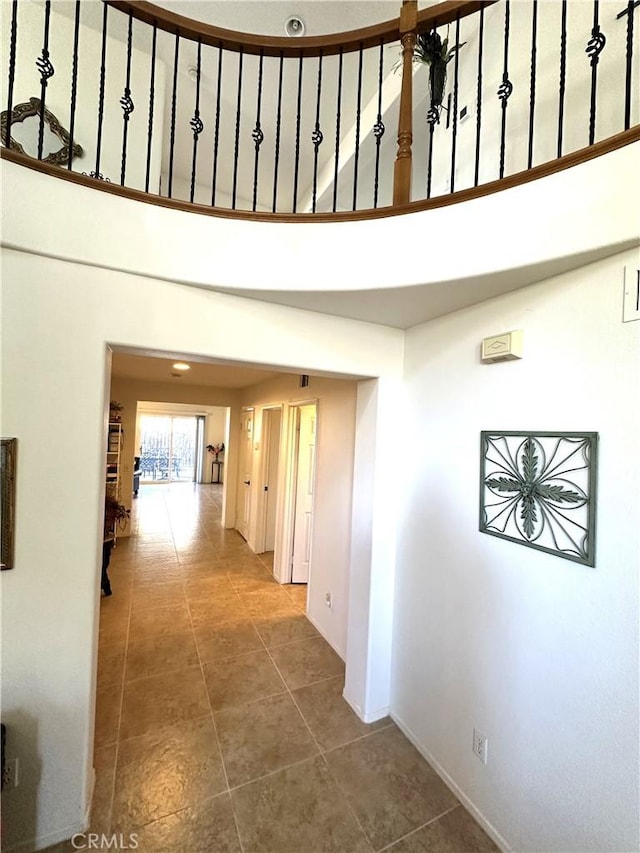 corridor featuring tile patterned floors and a high ceiling