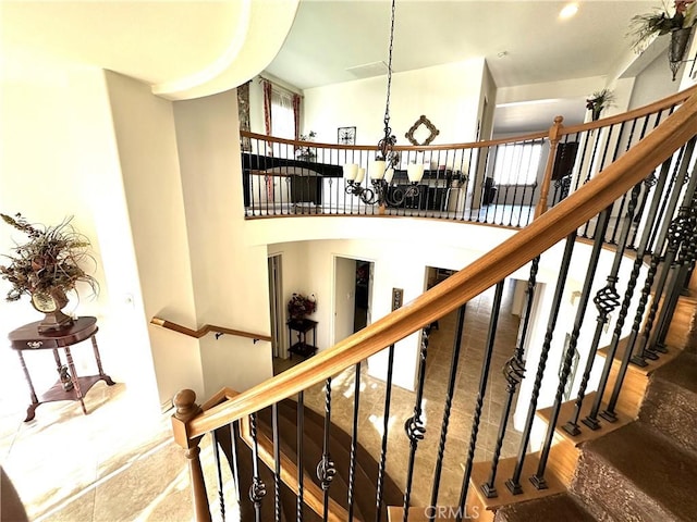 stairway featuring a healthy amount of sunlight, a chandelier, and a high ceiling