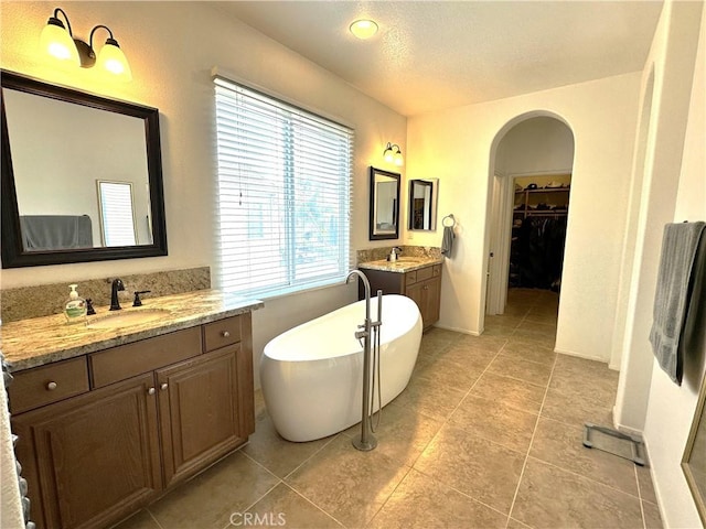 bathroom with tile patterned floors, vanity, and a bath