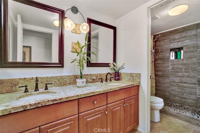 bathroom with tiled shower, vanity, and toilet