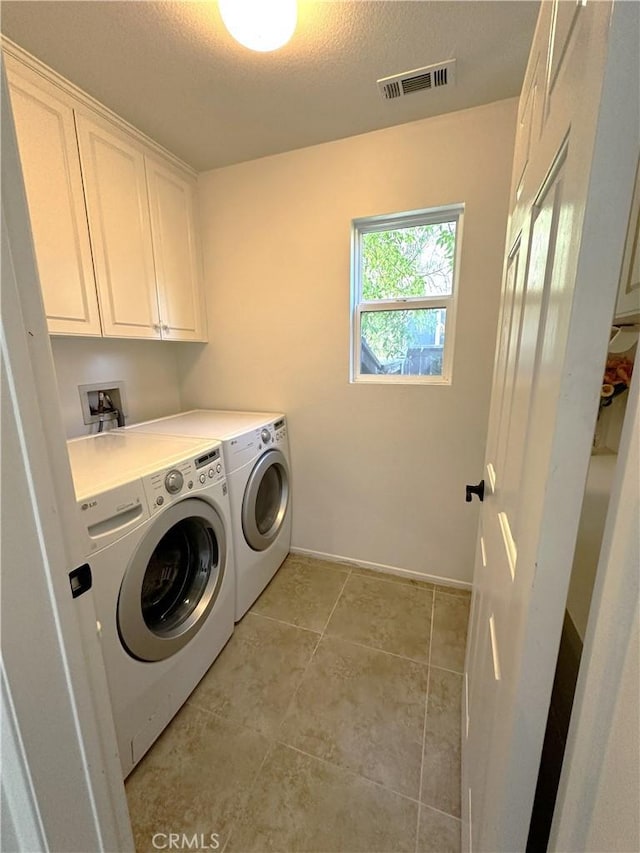 washroom with cabinets, light tile patterned floors, washer and dryer, and a textured ceiling