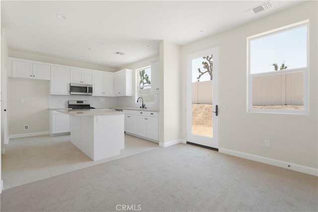 kitchen with white cabinetry, range, sink, and a kitchen island