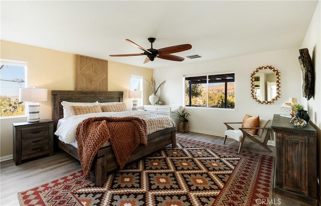 bedroom with multiple windows, hardwood / wood-style floors, and ceiling fan