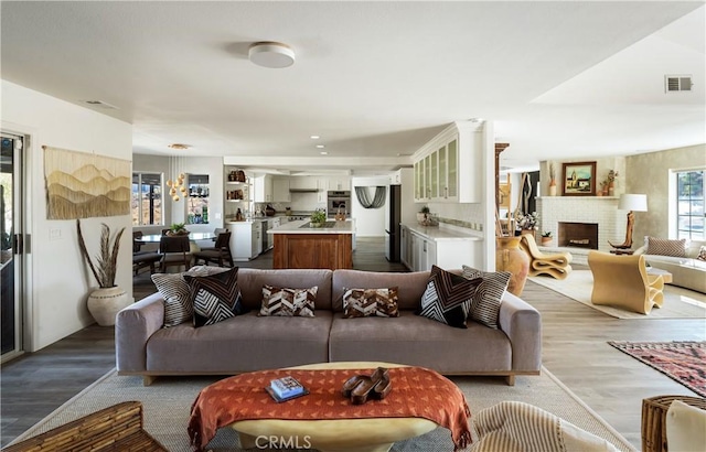 living room featuring a brick fireplace and wood-type flooring