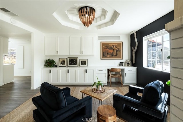 living room featuring a notable chandelier, dark hardwood / wood-style flooring, and a tray ceiling