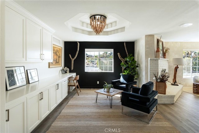 sitting room with an inviting chandelier, plenty of natural light, a tray ceiling, and wood-type flooring