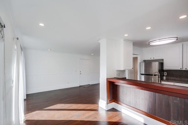 kitchen with sink, stainless steel fridge, white cabinets, backsplash, and dark wood-type flooring