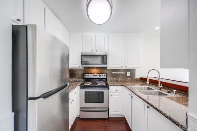 kitchen with sink, dark wood-type flooring, white cabinetry, dark stone countertops, and stainless steel appliances