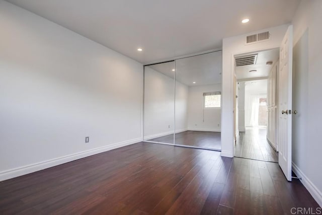 unfurnished bedroom with dark hardwood / wood-style flooring and a closet