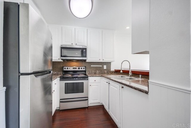 kitchen featuring sink, white cabinetry, appliances with stainless steel finishes, dark hardwood / wood-style floors, and dark stone counters