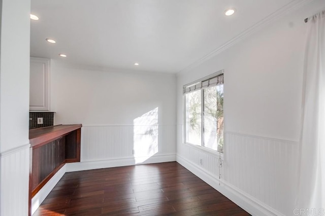 unfurnished dining area featuring ornamental molding and dark hardwood / wood-style flooring