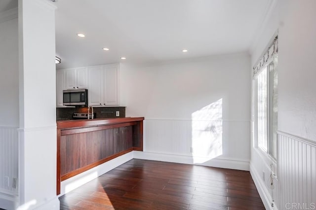 kitchen with ornamental molding, dark hardwood / wood-style floors, white cabinets, and backsplash