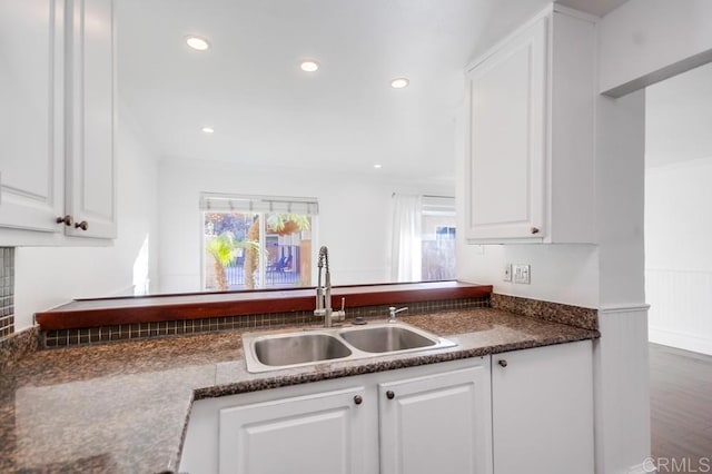 kitchen with white cabinetry, sink, and dark stone counters