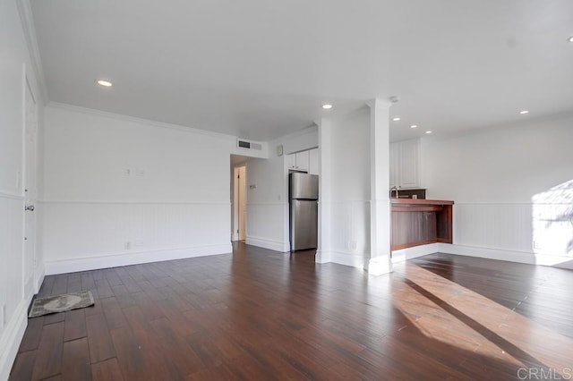 unfurnished living room featuring dark wood-type flooring and ornamental molding