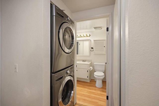 laundry room with hardwood / wood-style flooring and stacked washer / dryer