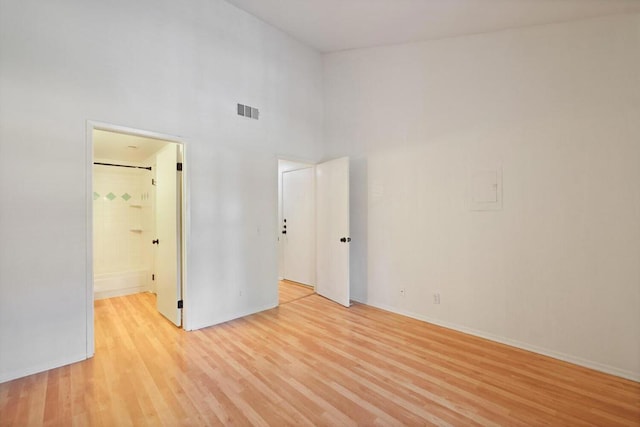 unfurnished room with a towering ceiling and light wood-type flooring