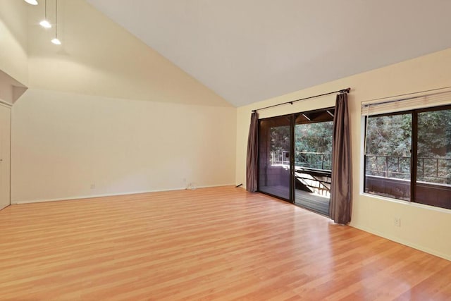 empty room with high vaulted ceiling and light hardwood / wood-style flooring