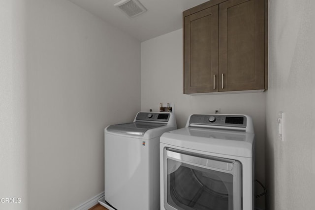 laundry room with separate washer and dryer and cabinets