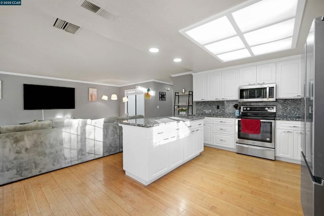 kitchen with stainless steel appliances, tasteful backsplash, dark stone countertops, and white cabinets