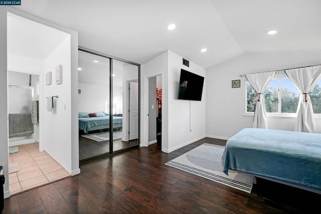 bedroom featuring connected bathroom, dark wood-type flooring, a closet, and vaulted ceiling