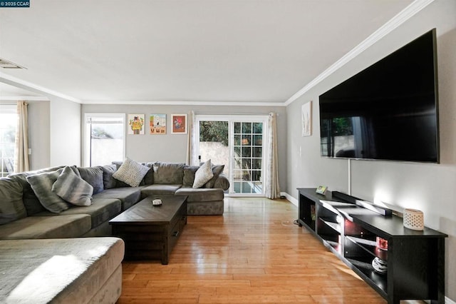 living room featuring crown molding, plenty of natural light, and light hardwood / wood-style flooring