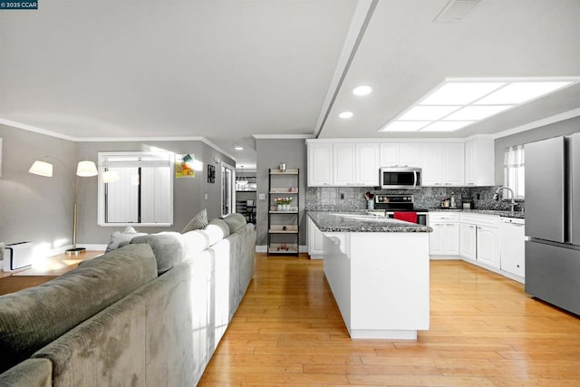 kitchen with white cabinetry, dark stone counters, a center island, light hardwood / wood-style floors, and stainless steel appliances