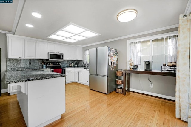 kitchen with white cabinetry, appliances with stainless steel finishes, plenty of natural light, and dark stone countertops