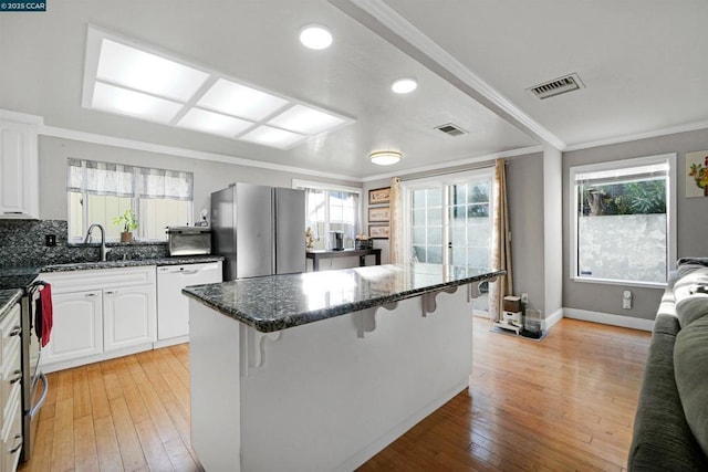 kitchen with white cabinetry, sink, stainless steel appliances, and a breakfast bar