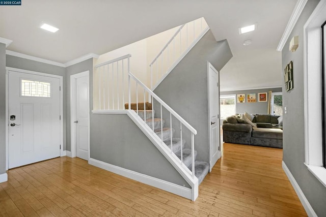 foyer entrance featuring crown molding and light hardwood / wood-style flooring