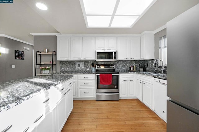 kitchen featuring appliances with stainless steel finishes, white cabinetry, sink, dark stone countertops, and decorative backsplash