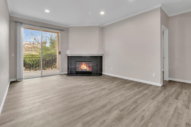 unfurnished living room with a tile fireplace, crown molding, and light hardwood / wood-style flooring