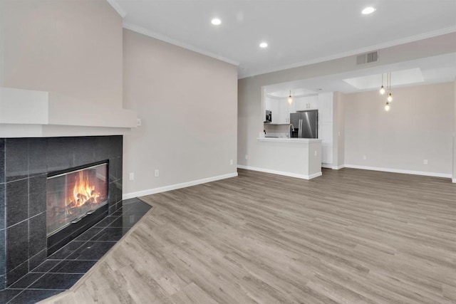 unfurnished living room with ornamental molding, dark hardwood / wood-style flooring, and a tiled fireplace