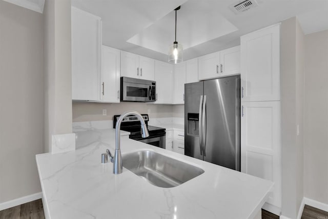 kitchen featuring hanging light fixtures, appliances with stainless steel finishes, white cabinets, and light stone counters