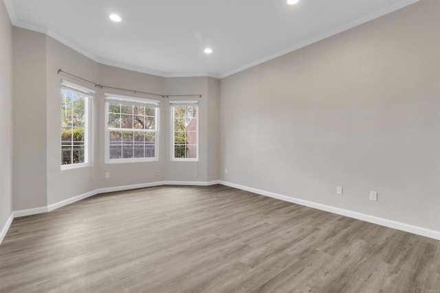 empty room with ornamental molding and light hardwood / wood-style floors