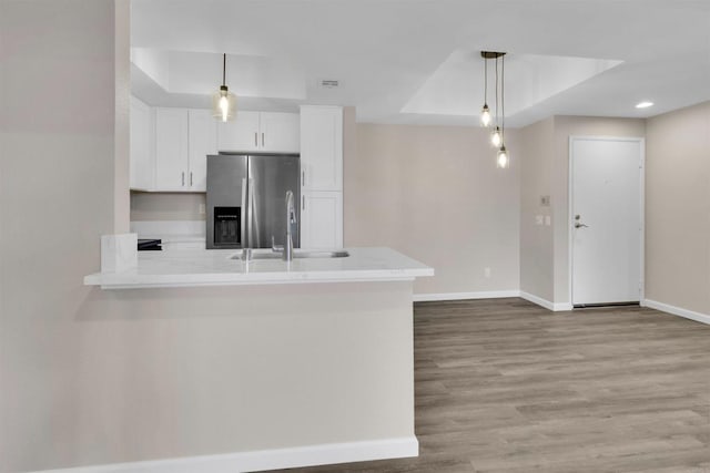 kitchen featuring sink, white cabinetry, decorative light fixtures, stainless steel fridge with ice dispenser, and a raised ceiling