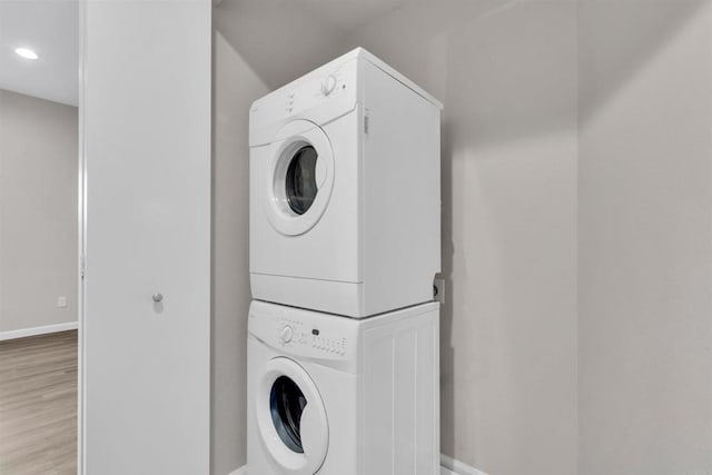 clothes washing area featuring stacked washer and dryer and light wood-type flooring