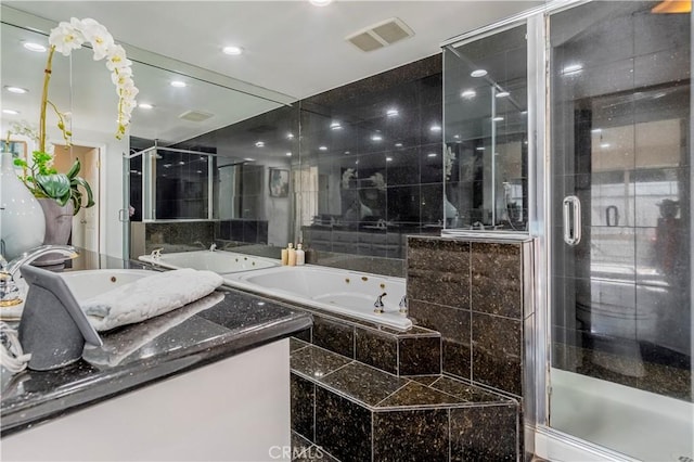 bathroom featuring vanity, independent shower and bath, and tile walls