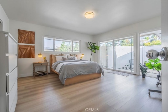 bedroom featuring multiple windows, access to exterior, and light hardwood / wood-style flooring