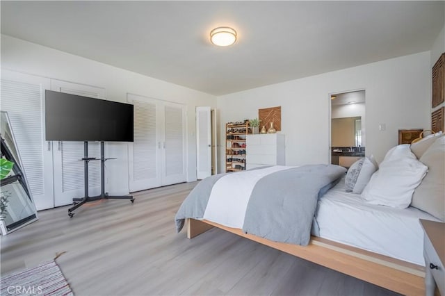 bedroom featuring multiple closets and light hardwood / wood-style flooring