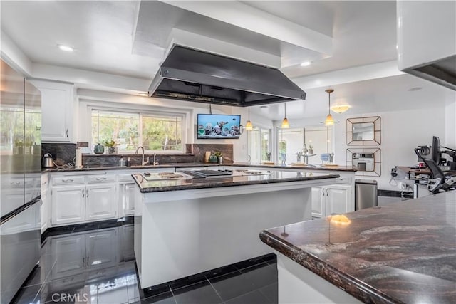 kitchen featuring tasteful backsplash, white cabinetry, island exhaust hood, and dark tile patterned floors