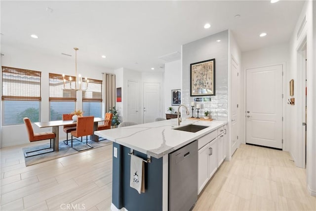 kitchen with decorative light fixtures, dishwasher, sink, white cabinets, and light stone countertops