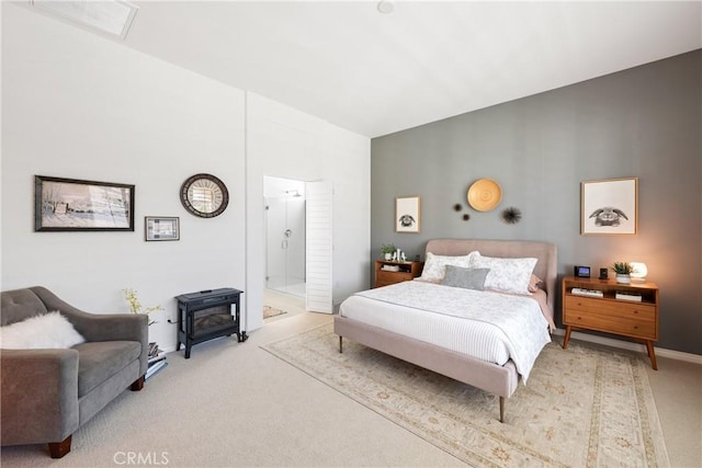 bedroom with light colored carpet, connected bathroom, and a wood stove