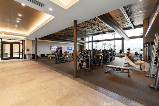 exercise room with a tray ceiling, french doors, and a high ceiling