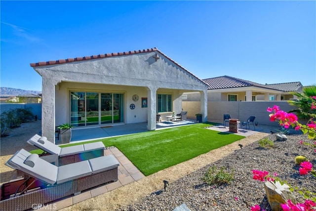 back of house with a patio area, a lawn, and an outdoor fire pit