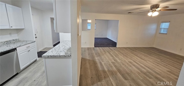 kitchen with light stone counters, white cabinets, and dishwasher