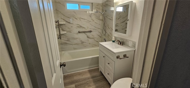 full bathroom featuring hardwood / wood-style flooring, tiled shower / bath, vanity, and toilet