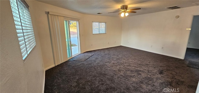 spare room with dark colored carpet and ceiling fan