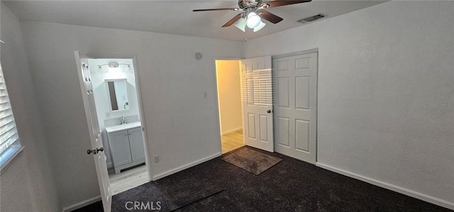 unfurnished bedroom with sink, ceiling fan, ensuite bathroom, light carpet, and a closet