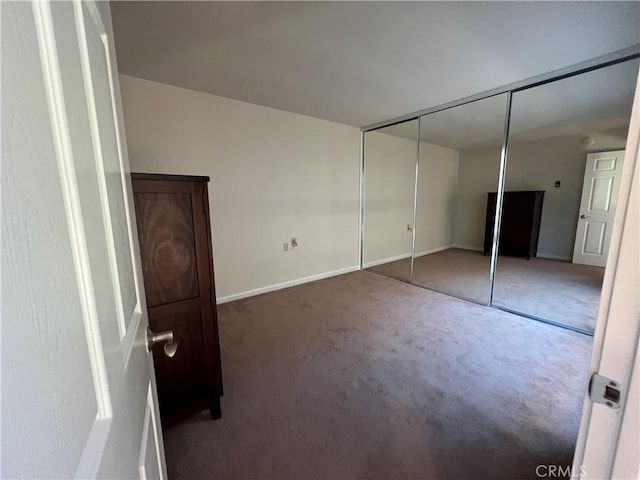 unfurnished bedroom with a closet and dark colored carpet