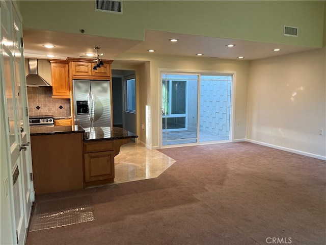 kitchen with dark stone countertops, appliances with stainless steel finishes, dark carpet, wall chimney range hood, and backsplash